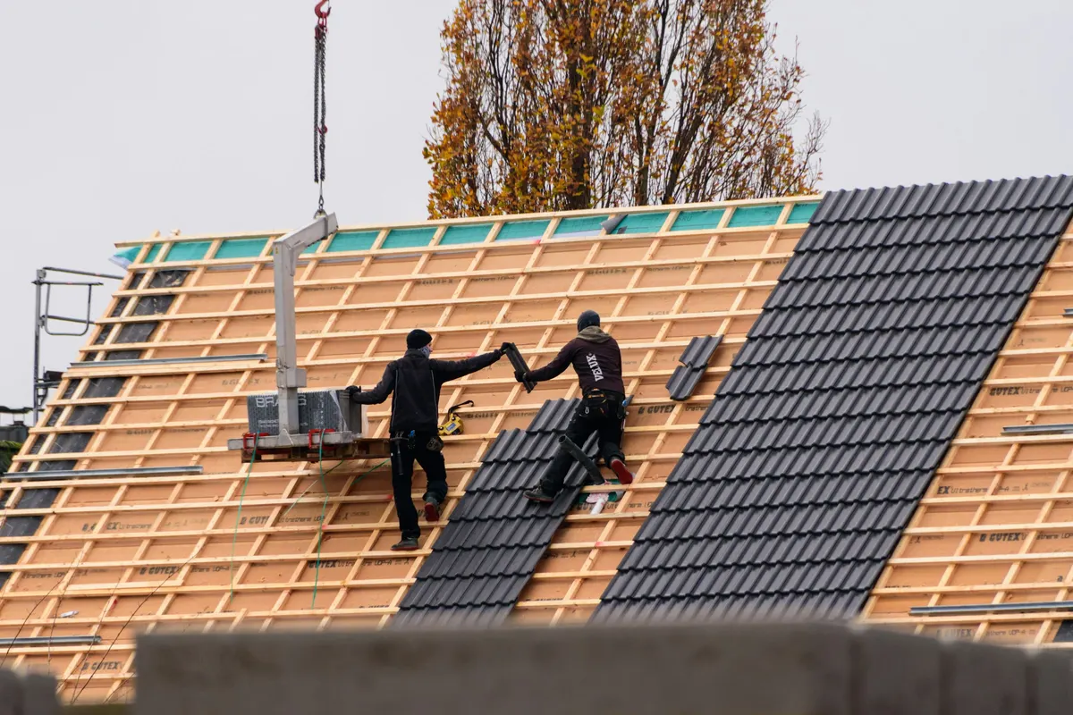 Symbolbild: Dachdecker verlegen Dachziegel auf einer neuen Lattung